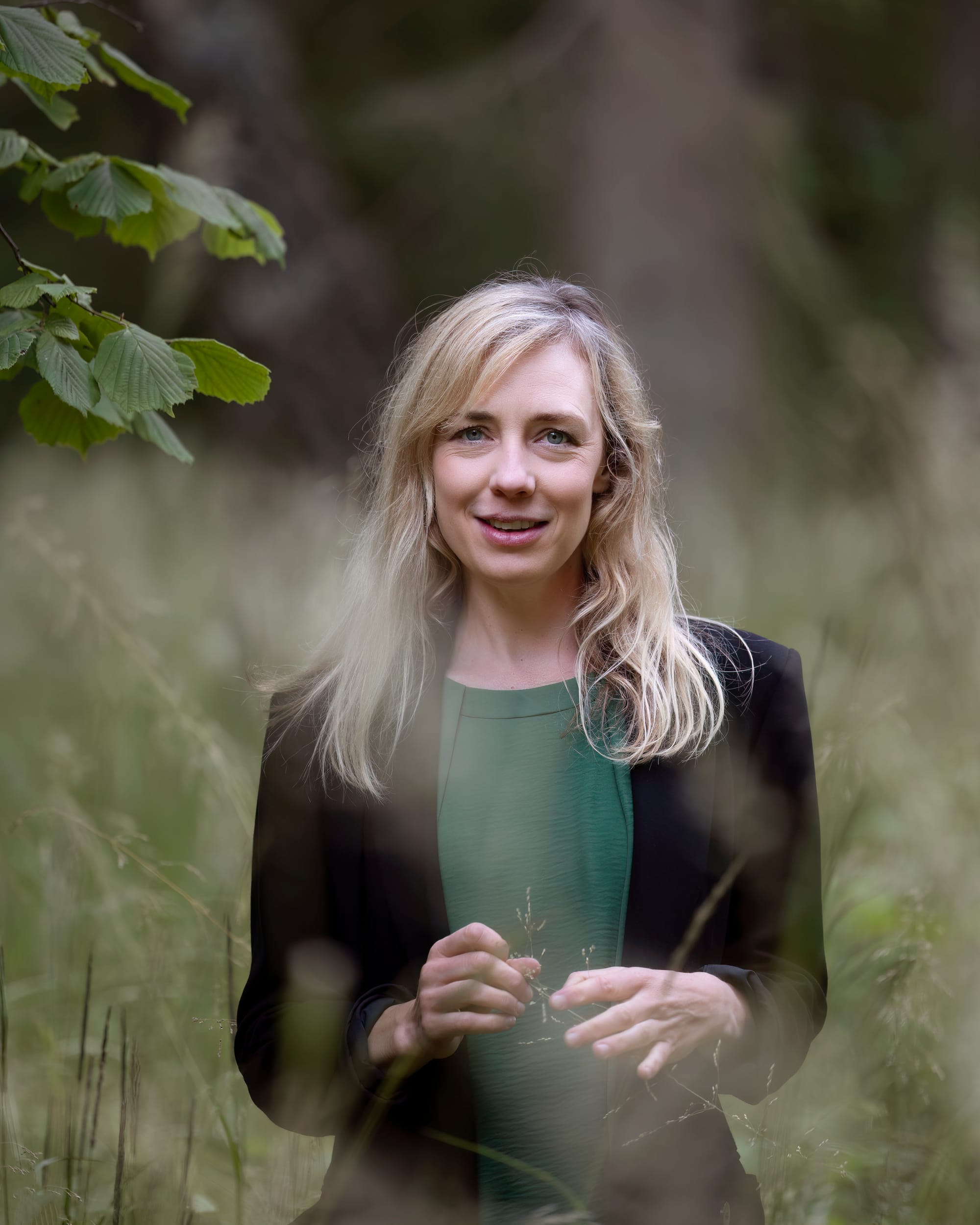 Bild på Lena Hammargren i grön tröja och svart kavaj på en äng.