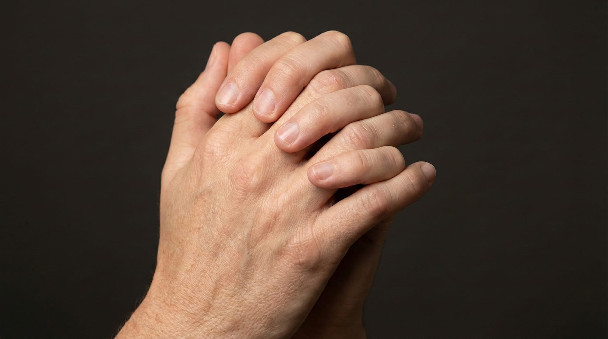 Close-up of two hands with interlaced fingers, like a prayer gesture