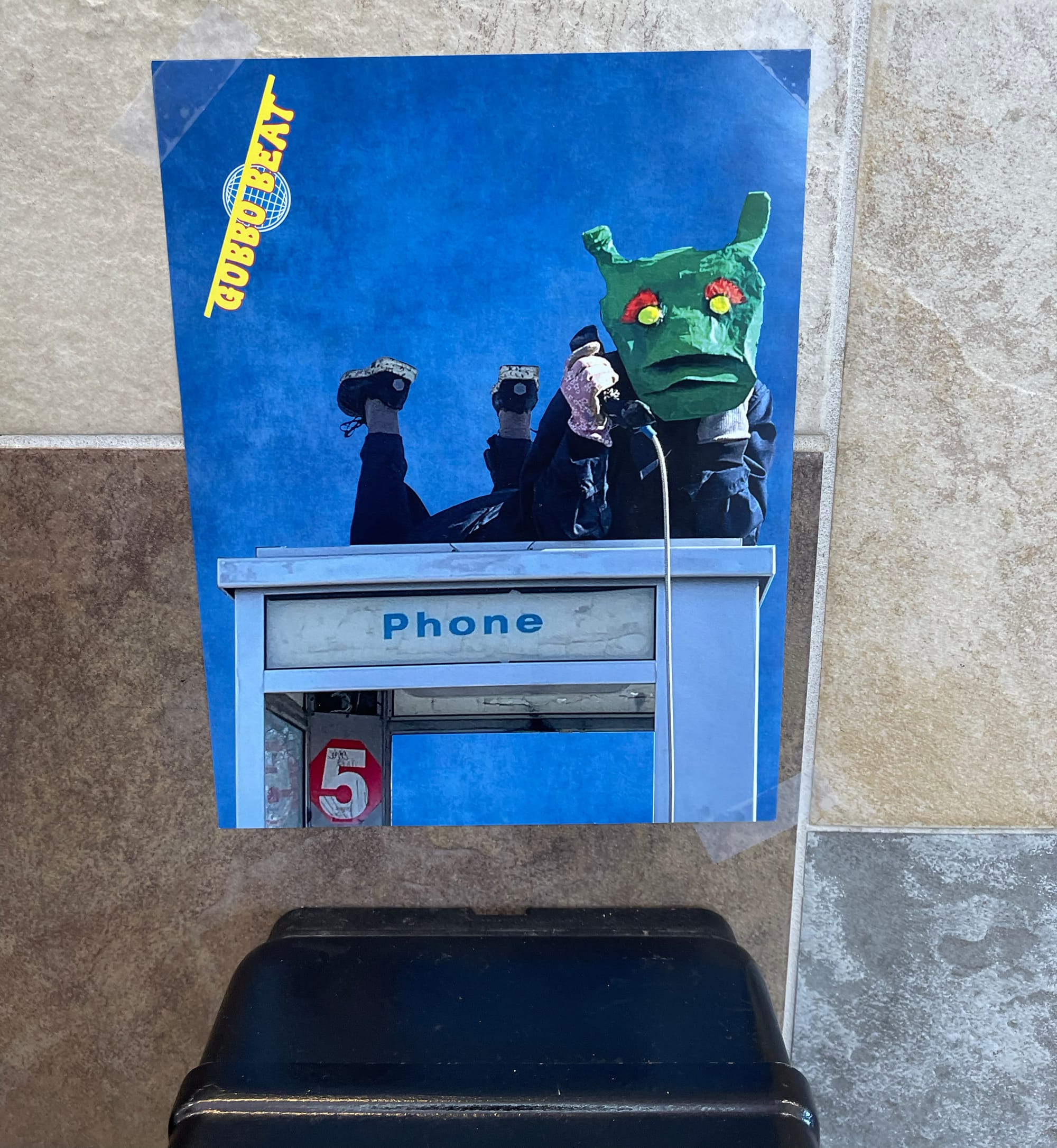 Gobbo Beat image featuring a member of Rotary Club affixed to the wall above a payphone at the Fourth Street Bus Station 