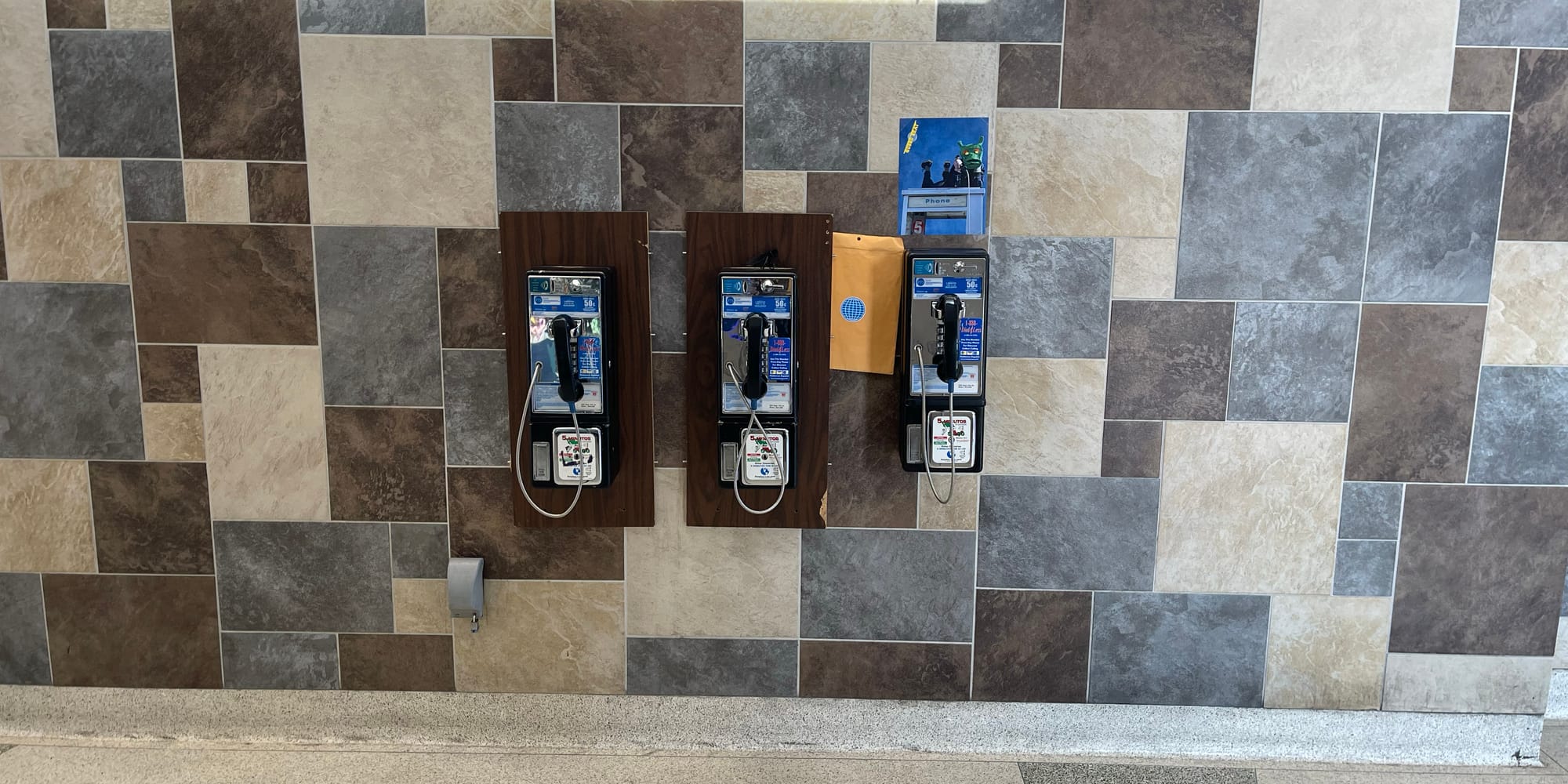 The manila envelope with instructions, quarters, and the Rotary Club logo lodged behind one of three payphones at the Fourth Street Bus Station in Reno. A photo of one of them in a mask atop a payphone was affixed to the wall.