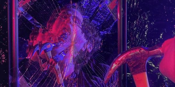 Evinspragg, holding a hammer, reflected in a broken mirror