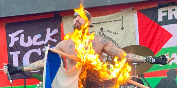 Haram performing at in Brooklyn (September 11, 2025). Frontman Nader stands in front of a banner that reads “FUCK ICE.” Someone in the front of the crowd burns the Israeli flag.