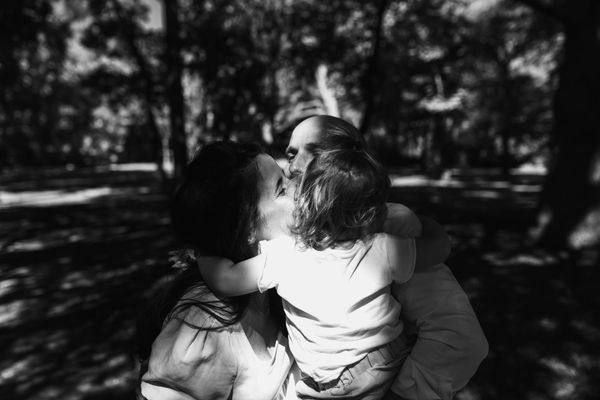 Mum, dad, and child hug on the day of mum and dad's wedding. Black and white photo © Sara Götz.