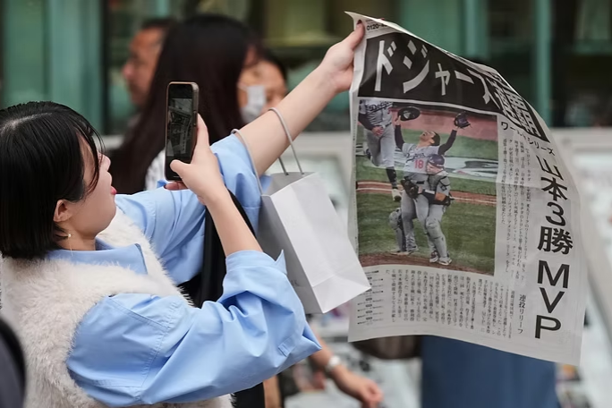 Una aficionada toma fotos de una publicación de la prensa japonesa este domingo tras el triunfo de los Dodgers en la Serie Mundial y la designación de Yoshinobu Yamamoto como el MPV de la serie. (Foto: Hiro Komae/AP)