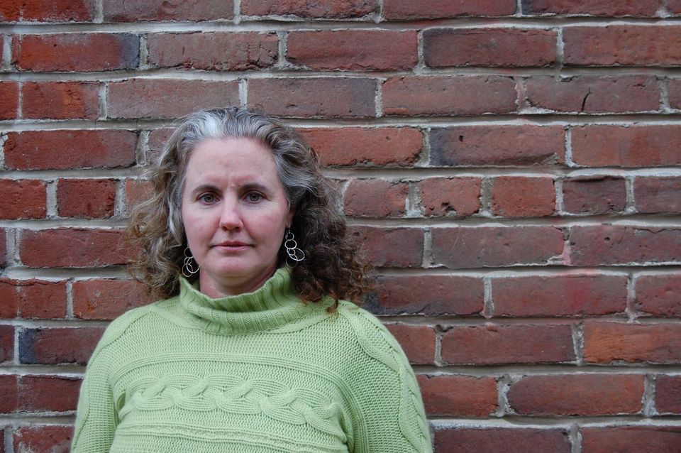 Christina looking forward in front of old brick wall