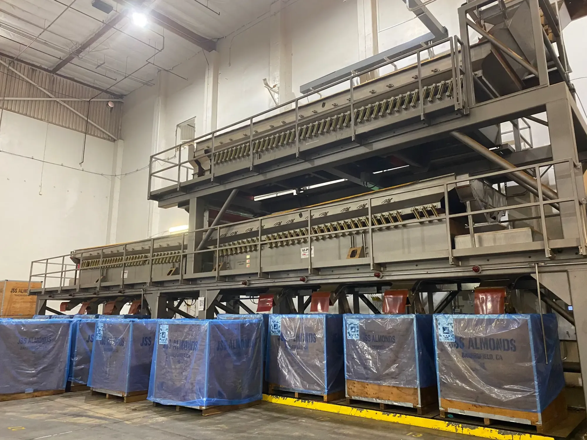 Multi-level almond sizing and grading system processing line with product totes at a California almond facility