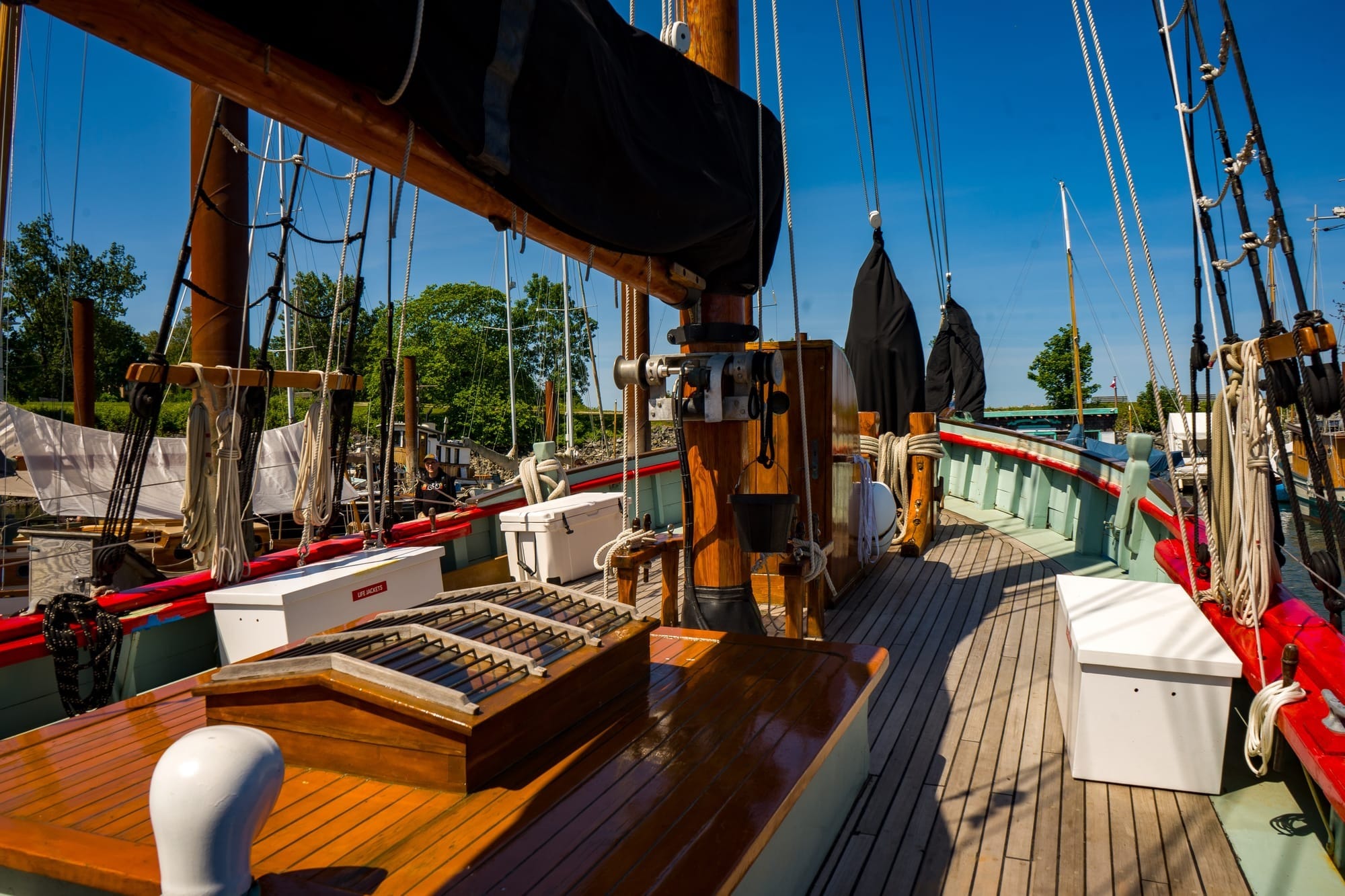 The deck of a wooden sailboat looking towards the bow.