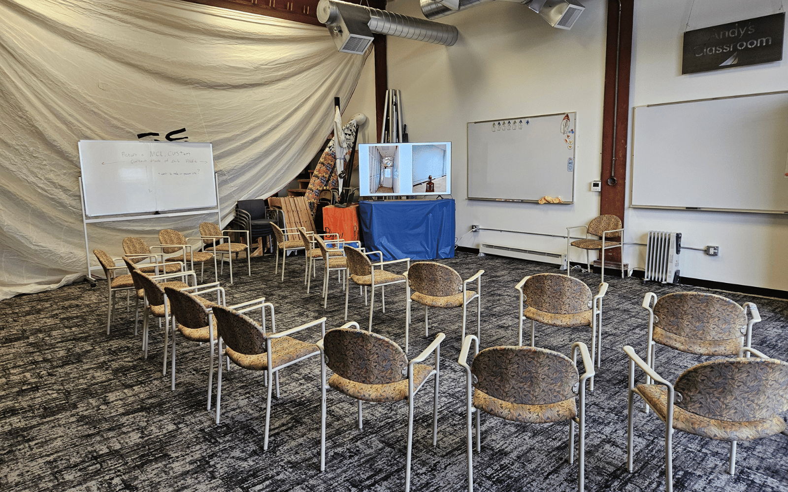 Empty chairs face whiteboards in a room with a sail curtain.