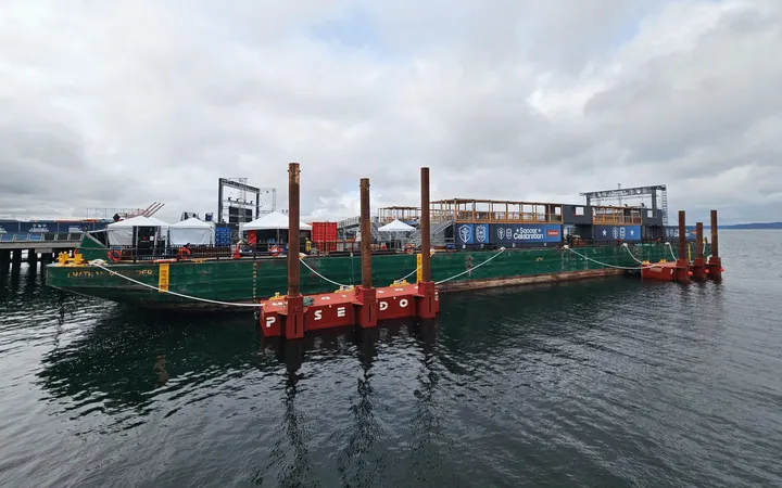 A green barge with tents and a stage with a large "Soccer Celebration" banner.