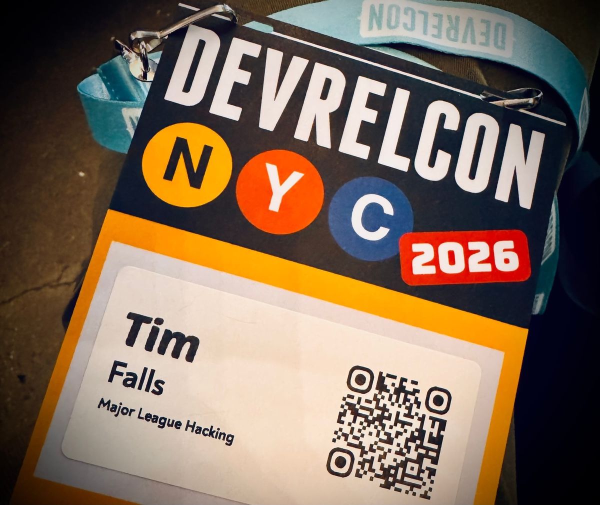 A close-up shot of a conference badge for DevRelCon NYC 2026, showing the name "Tim Falls" and "Major League Hacking" next to a QR code.