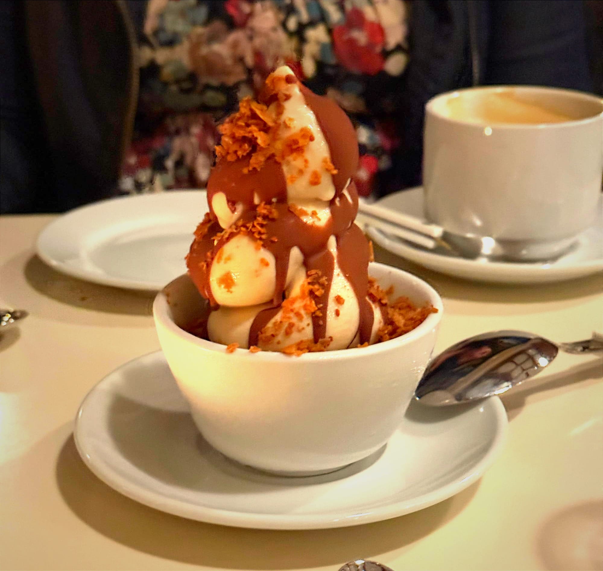 A bowl of soft serve with caramel and candied fruits.