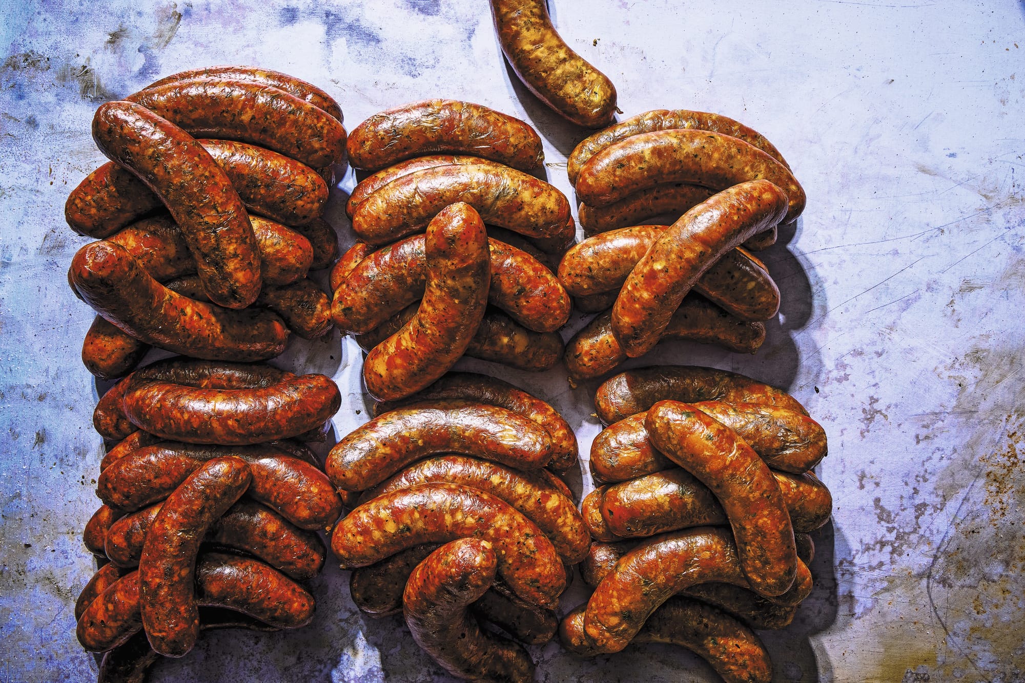 Dozens of sausages sit on top of each other in three rows.