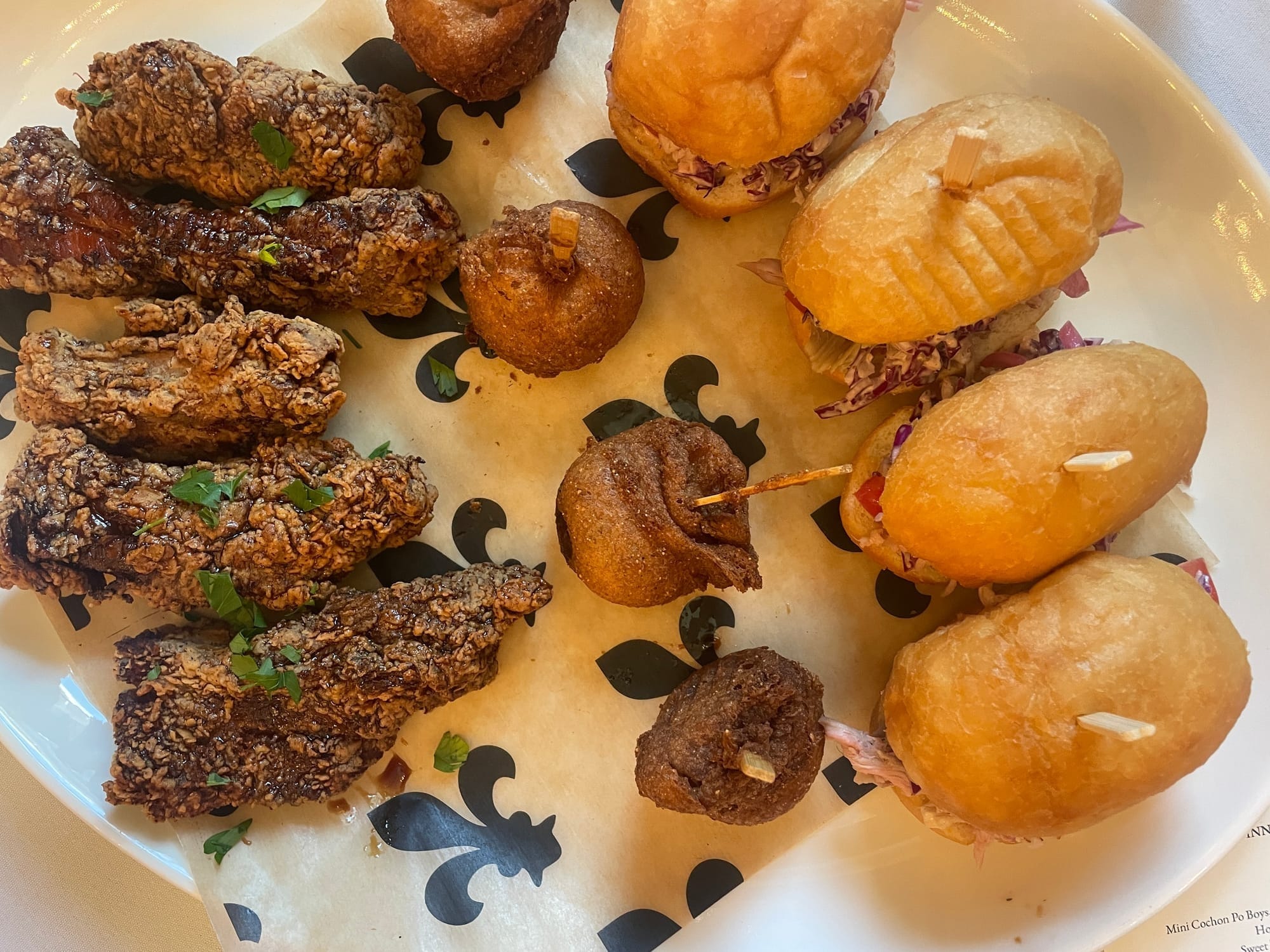 A plate holds deep-fried riblets, hush puppies, and pulled pork sandwiches.