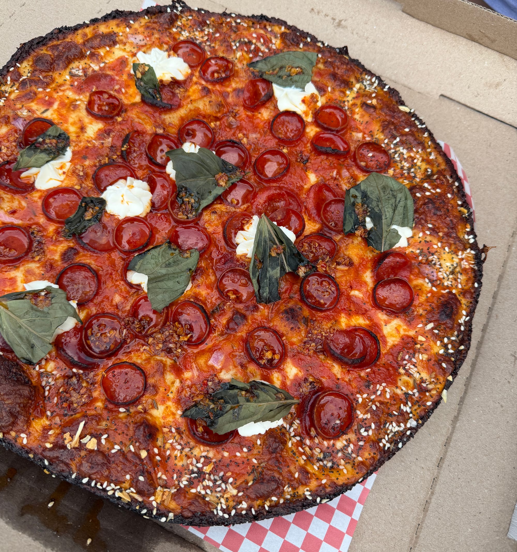 A pan pizza topped with pepperoni, basil, and ricotta with an everything bagel crust.
