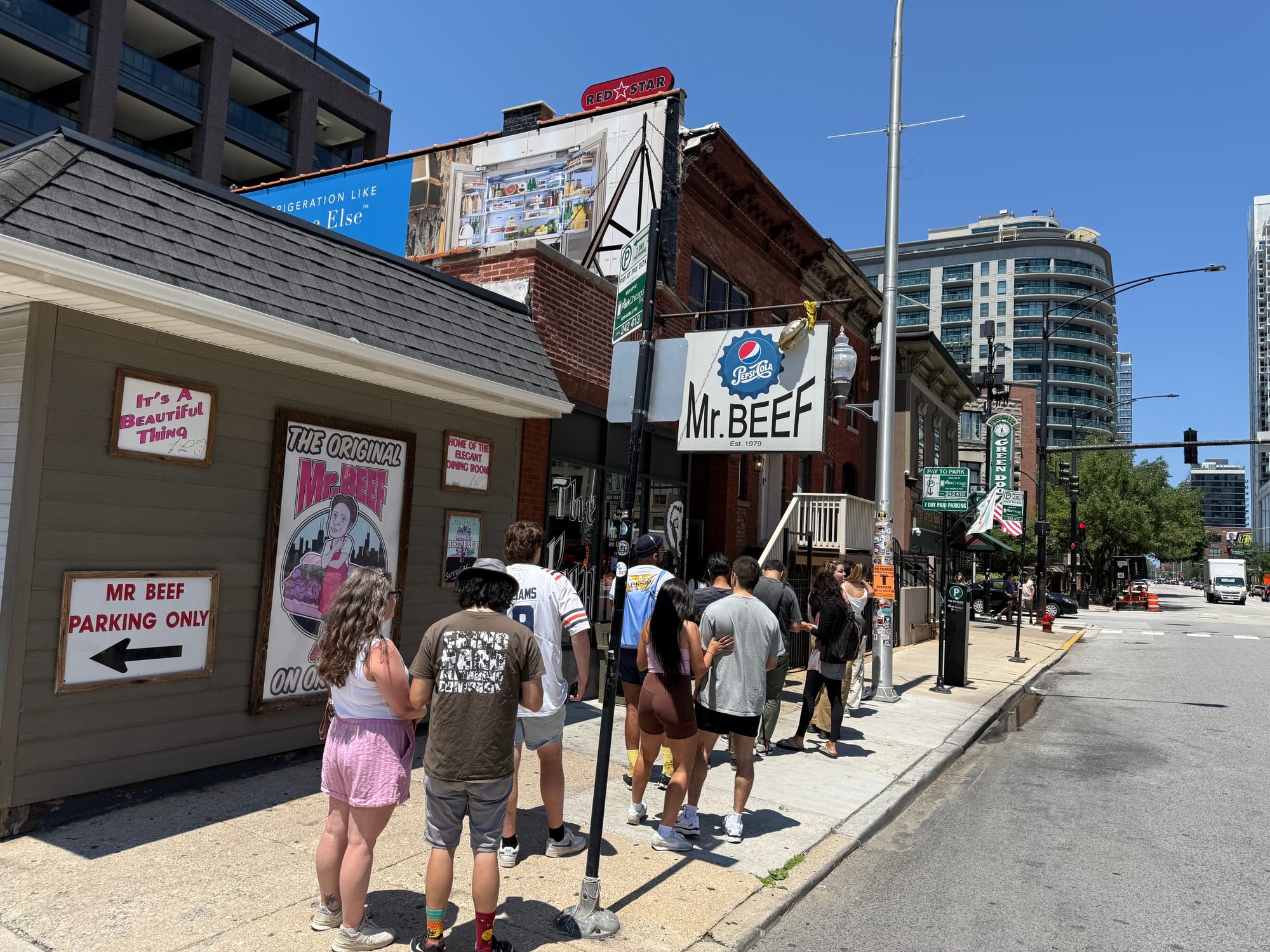 A group of about 15 people waiting on line at Mr. Beef in Chicago.