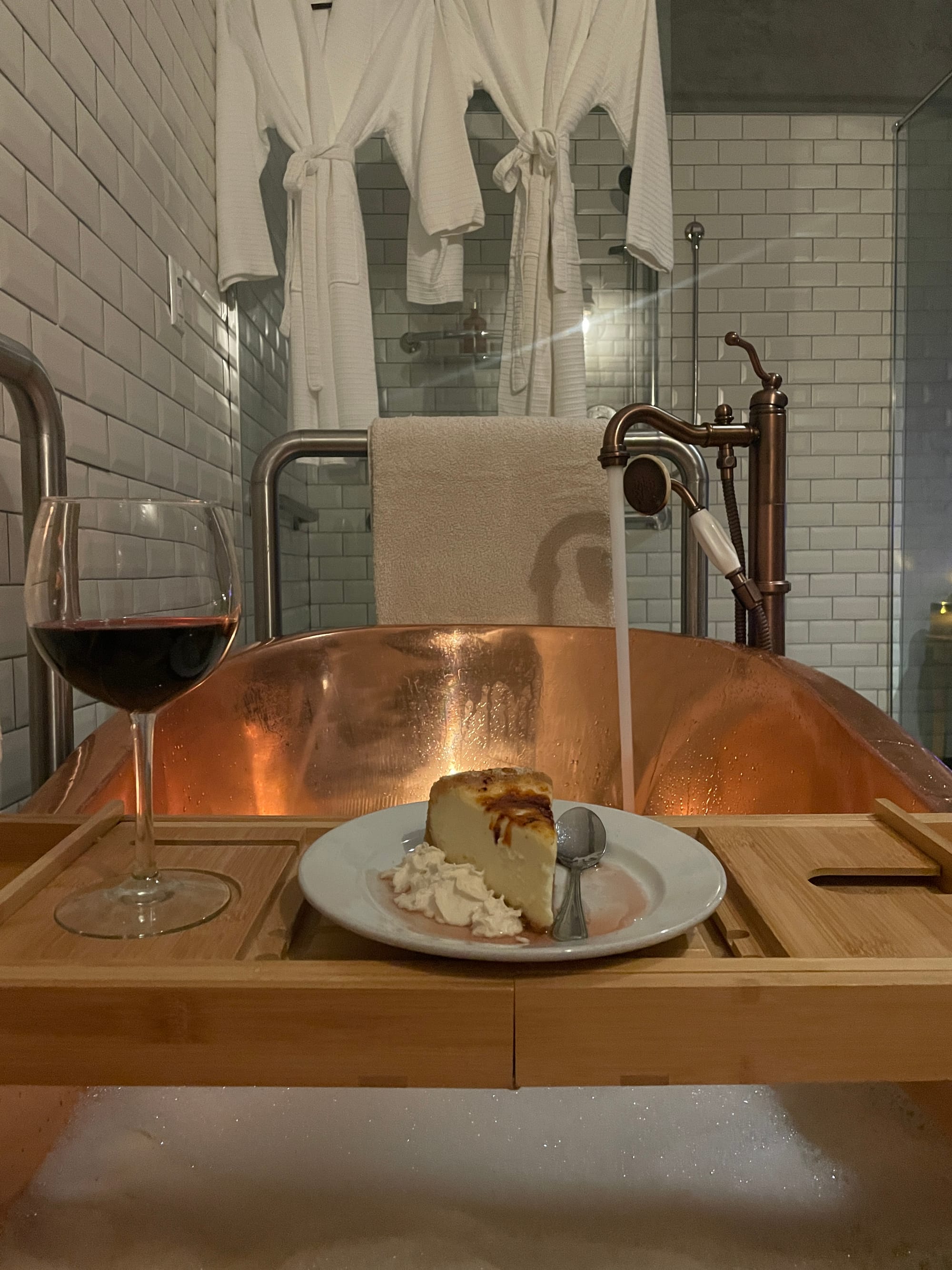 A tray with cheesecake on it sits above a copper tub filled with foamy water.