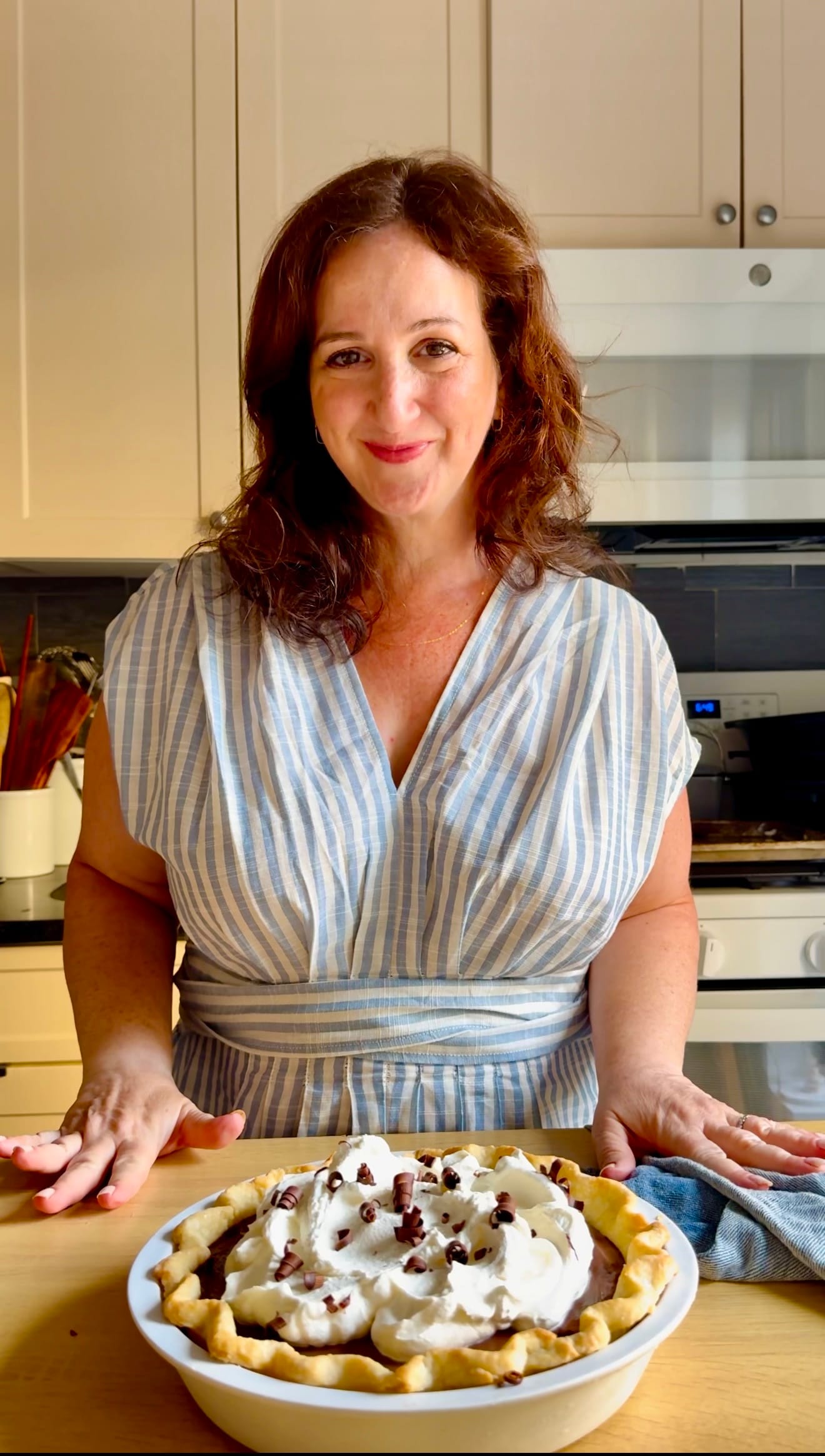 An image of a woman in a blue and white dress in front of a pie