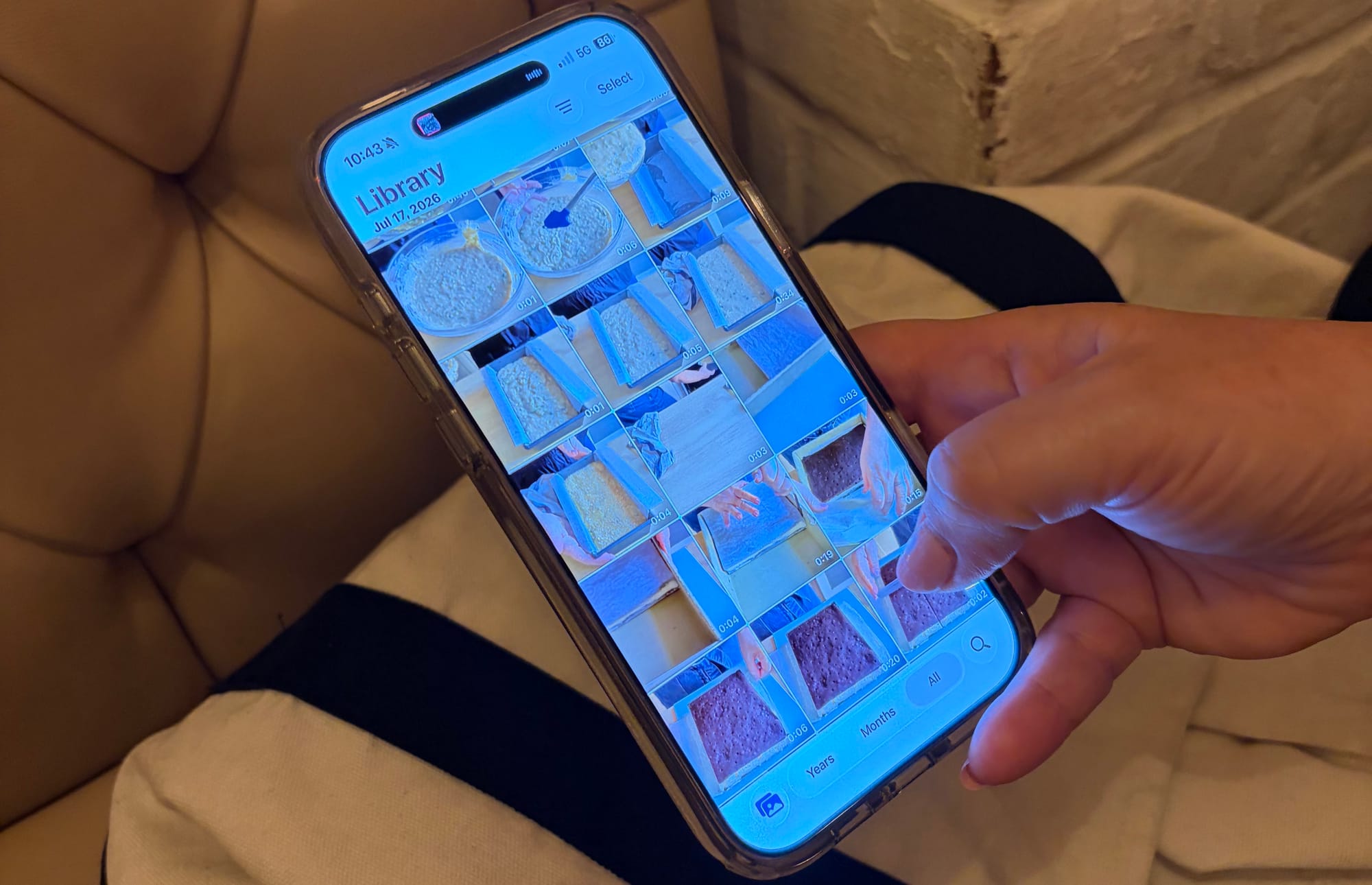 A hand scrolling through a phone photo library of food images
