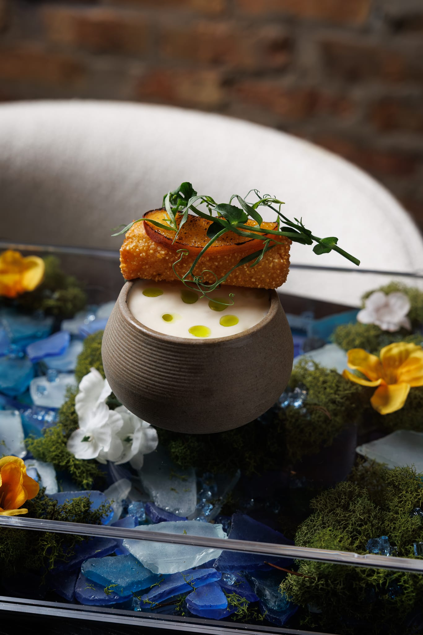 A bowl of soup with a fried fritter.