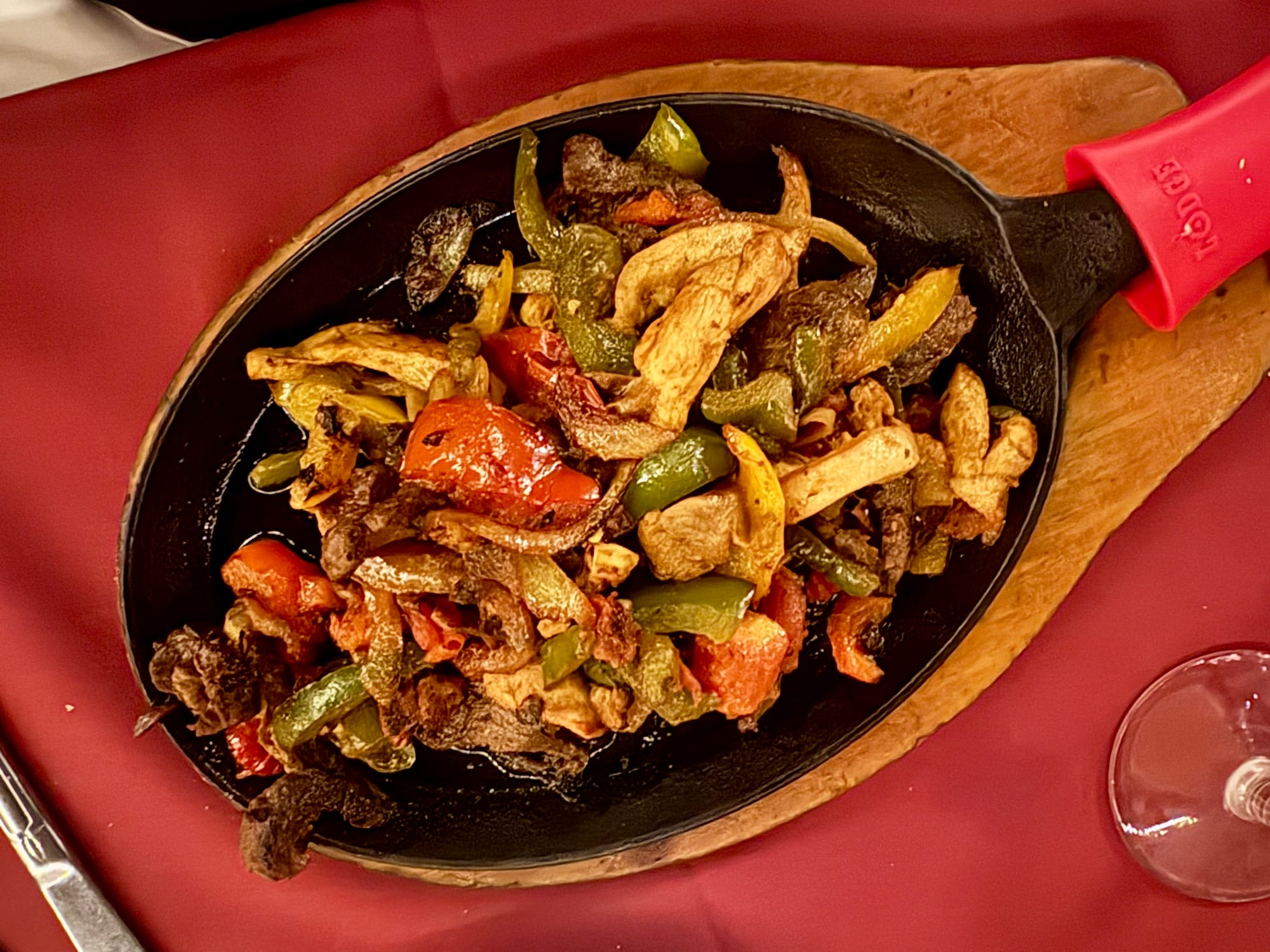 A skillet holds chicken, beef, bell peppers, onions, and tomatoes.