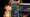 A toy robot and a laptop with ChatGPT on the screen in front of a fire background