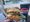 A hand holds a smashburger with guacamole and sauce coming out. A cup with the word Pepsi is to the right.