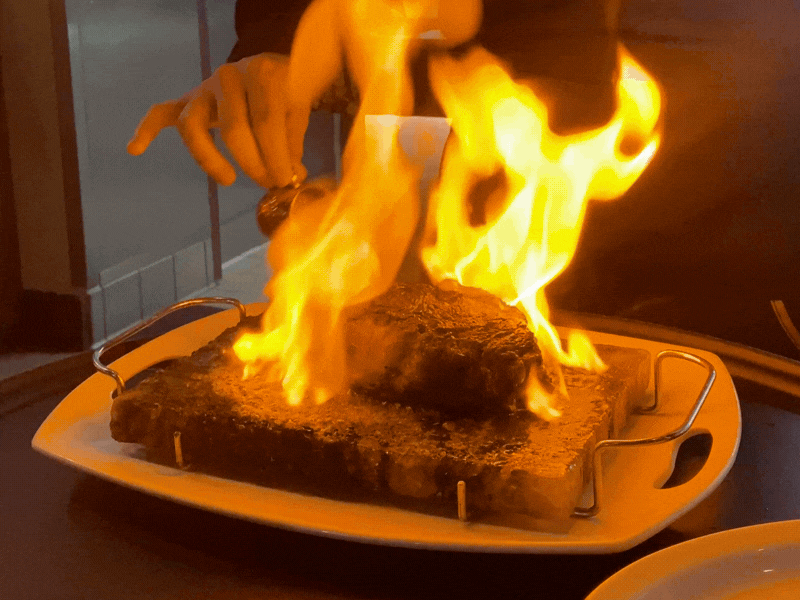 An animated gif of a steak being set on fire at a restaurant