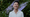 Chef Melissa King in a white button up shirt in front of greenery