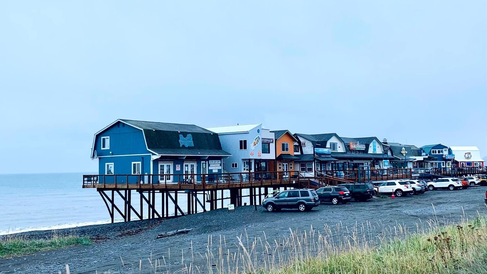 Row of wooden houses on stilts above the exposed shoreline in Homer, Alaska.