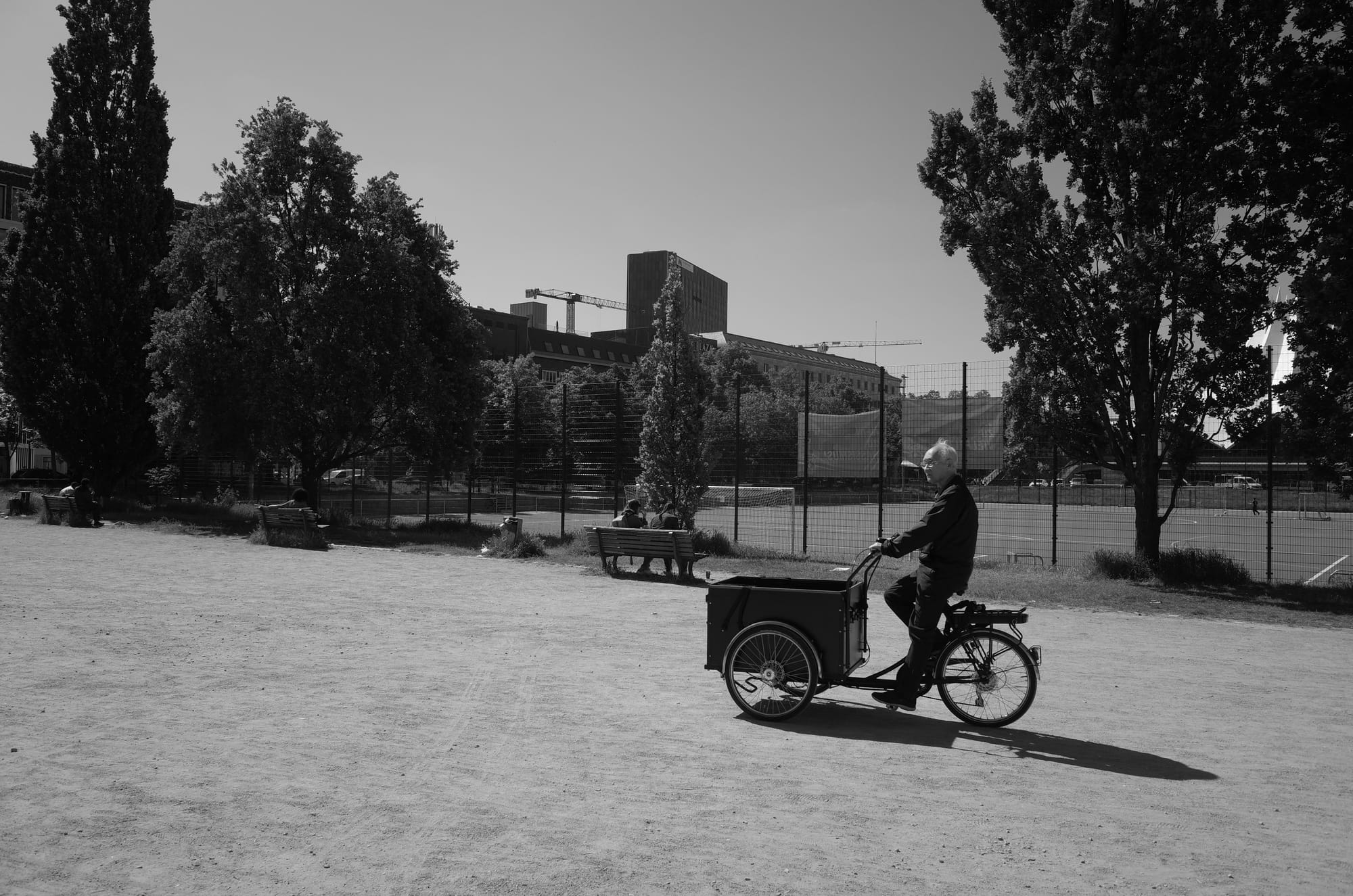 A man riding a bike through a dusty carpark