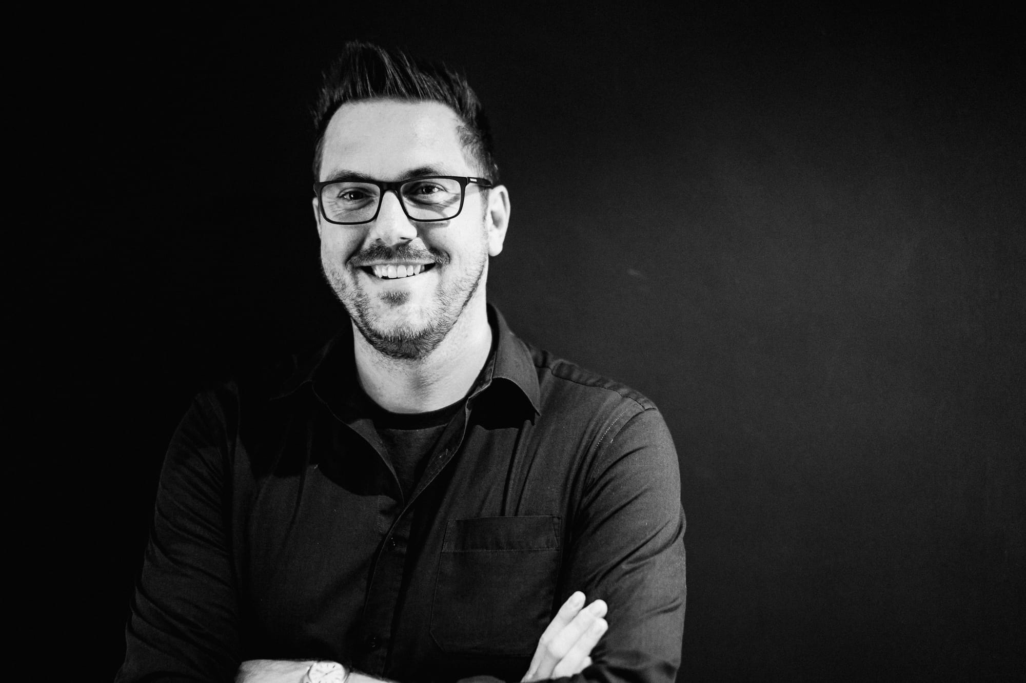 Rob Lambert, smiling, arms folded, in a black-and-white portrait
