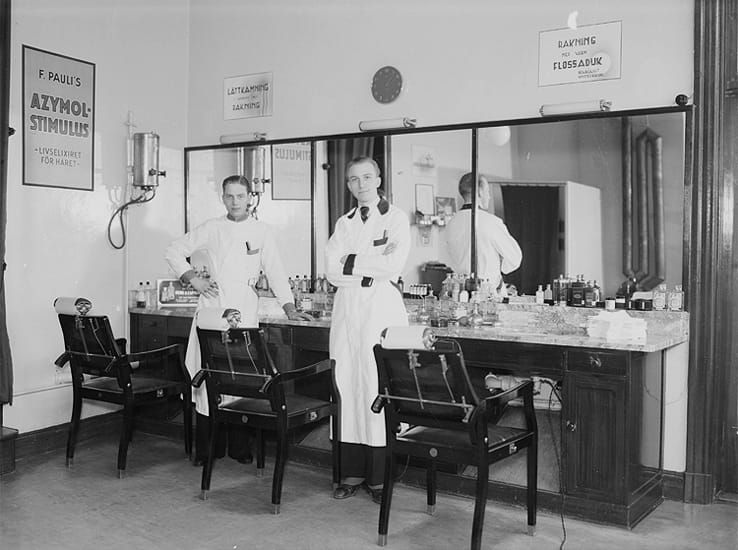 A photo of hairdressers - source: Frisörsalong, interiör, två frisörer. Martin Lindkvist by Borg, Knut - Örebro County Museum, Sweden - Public Domain.