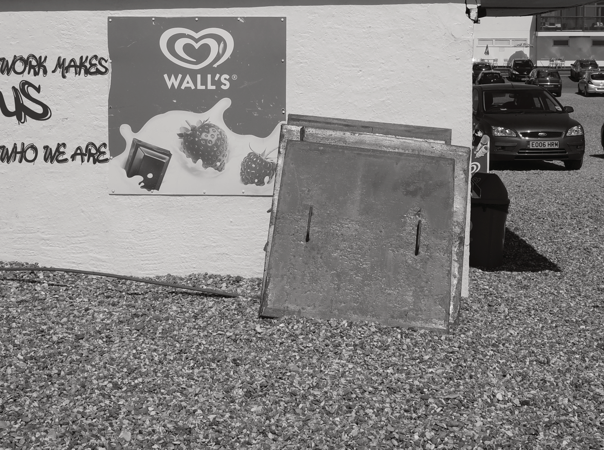 A photo of a wall by the sea with the words Work Makes Us Who We Are on it