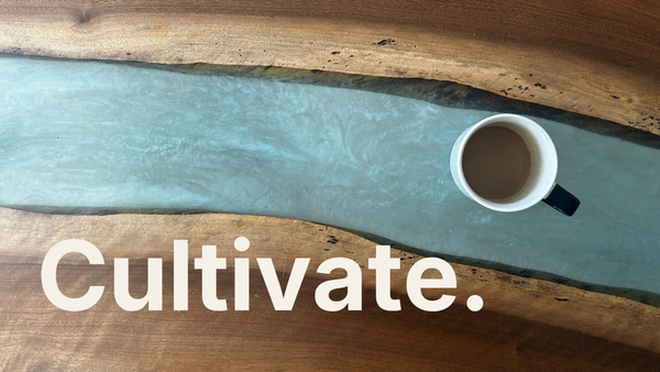 A photo of a coffee cup on a resin river table with the words overlaid. The Word at Work: Cultivate