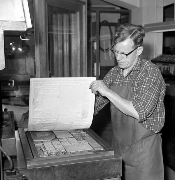 An old photo of someone printing a paper using a press - from Tidningstryckning by Andersson, Arne - Bohuslän Museum, Sweden - Public Domain.
