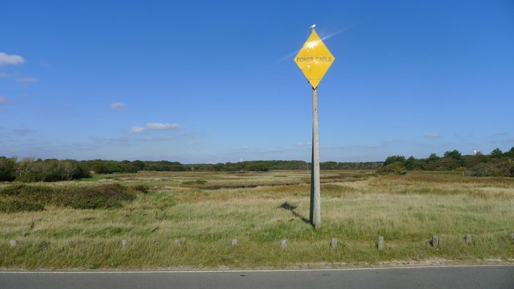 A photo of a lone power cable sign in a field