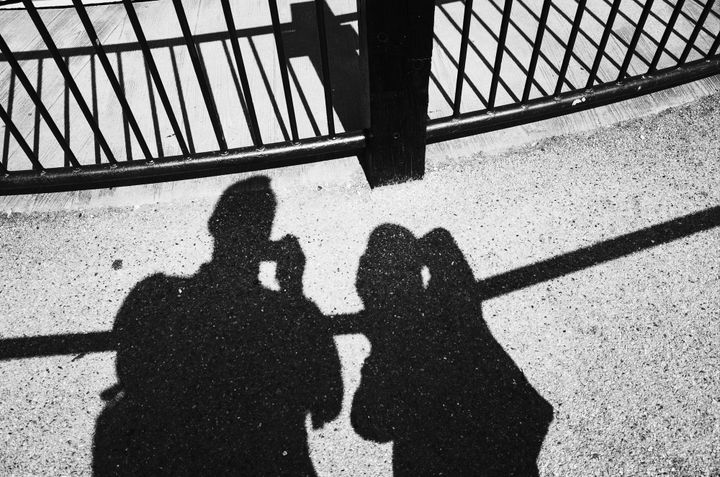 A shadow photo of two people by some railings