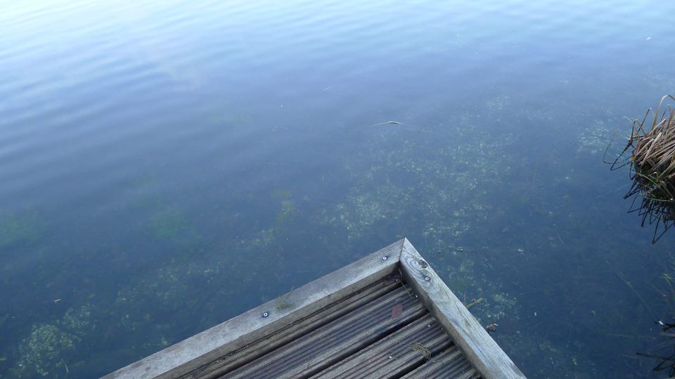 A photo of a pier edge with reflections and ripples in the water