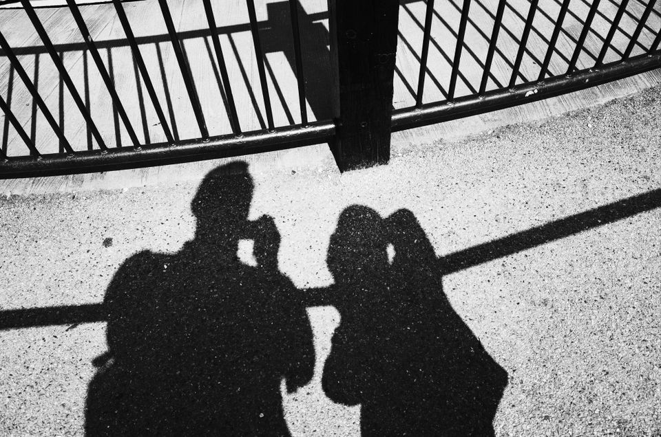 A shadow photo of two people by some railings