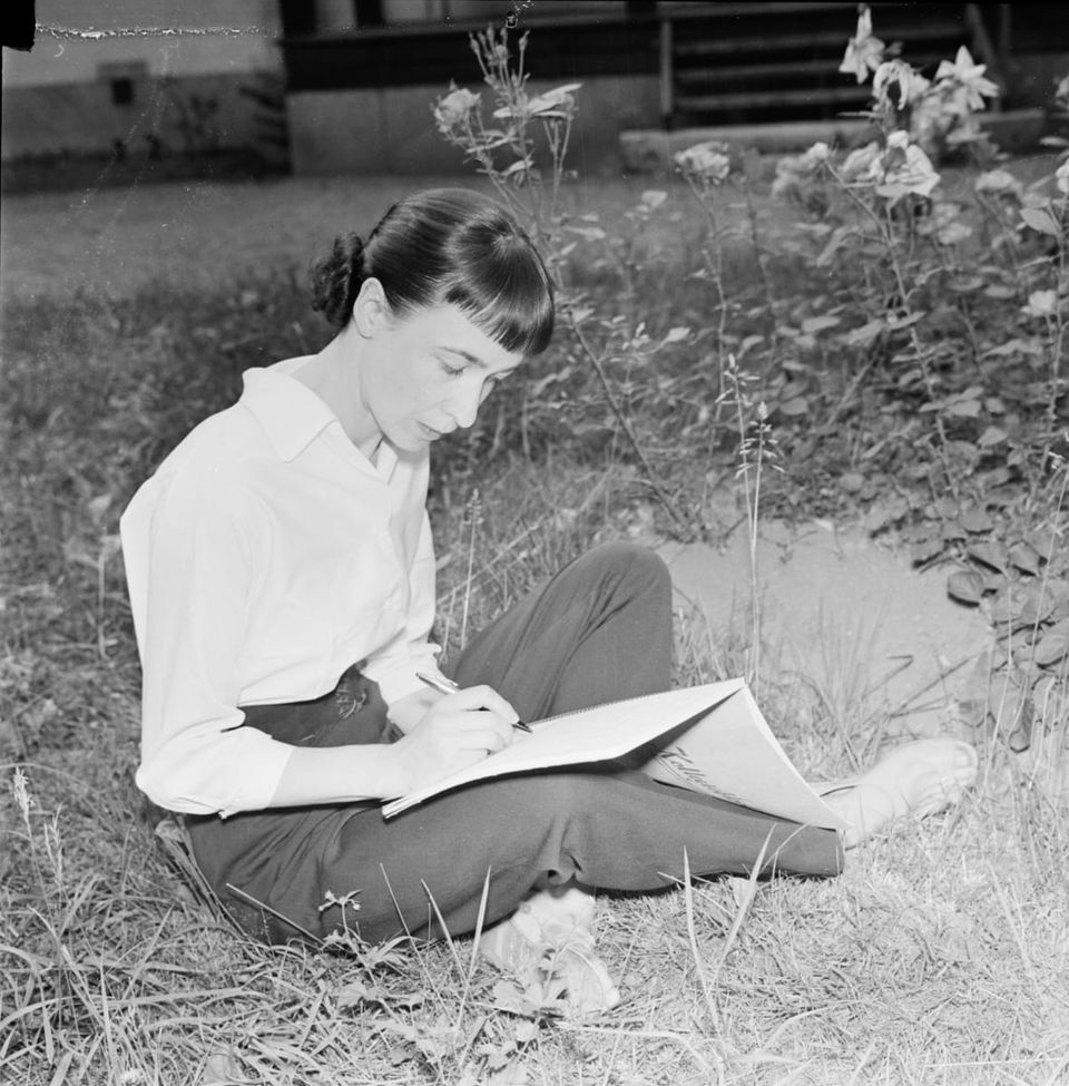 A photo from - Författarinnan Sara Lidman sitter ute i gräset och skriver, Uppsala 1955 by Uppsala-Bild - Upplands Museum, Sweden - CC BY-NC-ND.