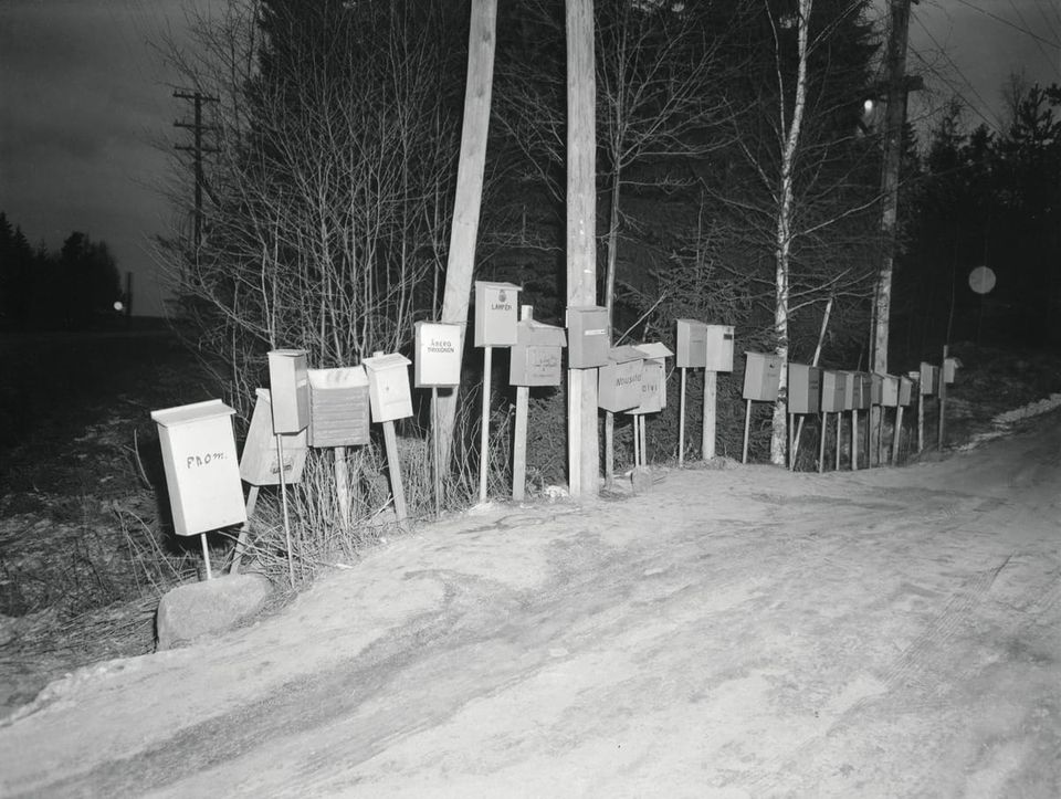 An old photo of letter boxes all next to each other - from: Letter boxes. by Voutilainen, Erkki - Finnish Heritage Agency, Finland - CC BY.