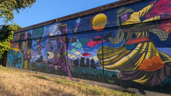 Vibrant mural on a concrete wall depicting different people from different cultures.