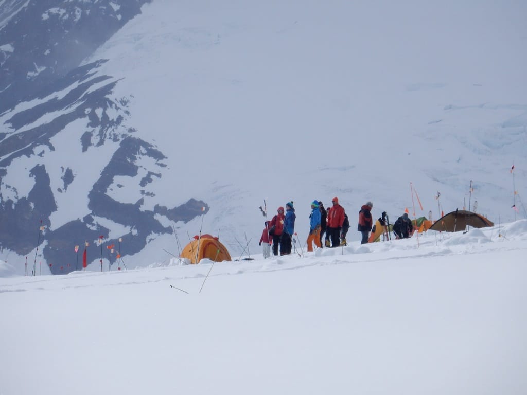 A band of brightly-colored climbers observe the comings and goings at the 'Kahiltna International Airport'. (NPS Photo/Steve Mock)