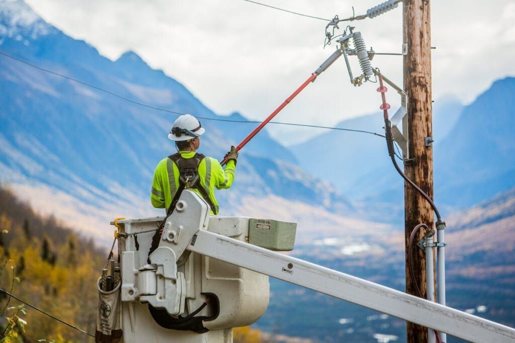 A worker with Matanuska Electric Association holds an insulated pole to reach and repair electrical lines.