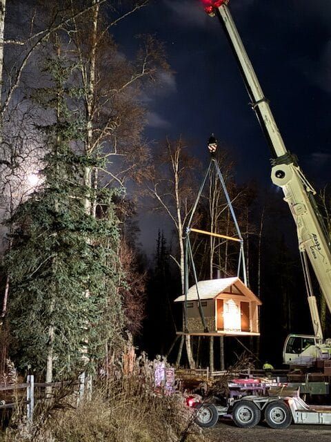 Pit toilets being hoisted by a crane and lowered into place at the Whigmi Trailhead parking area.
