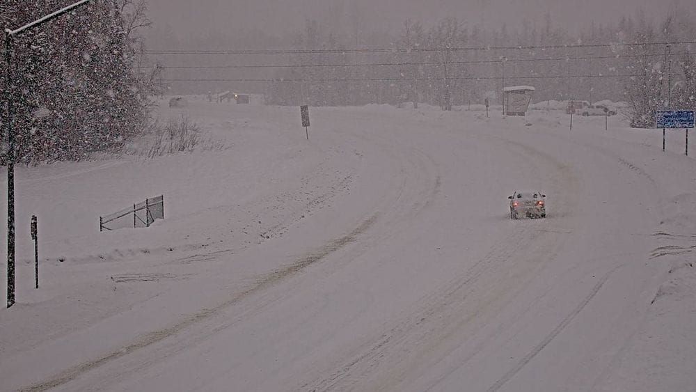 Alaska DOT camera footage showing the junction of Parks Highway with the Talkeetna Spur Road, with snowy and icy conditions.
