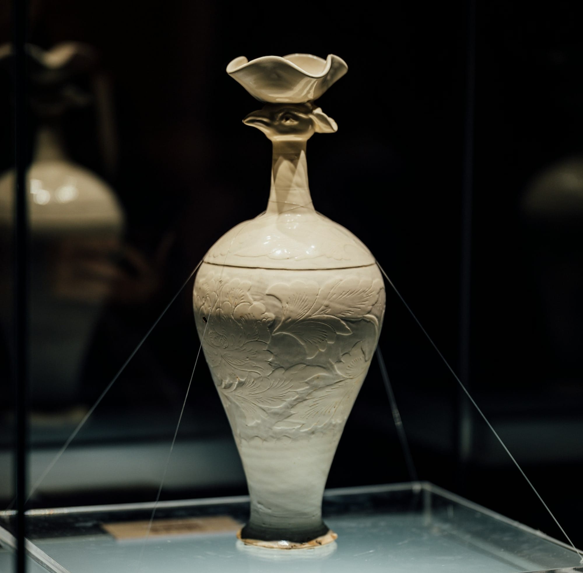 A white vase sitting on display in a glass case