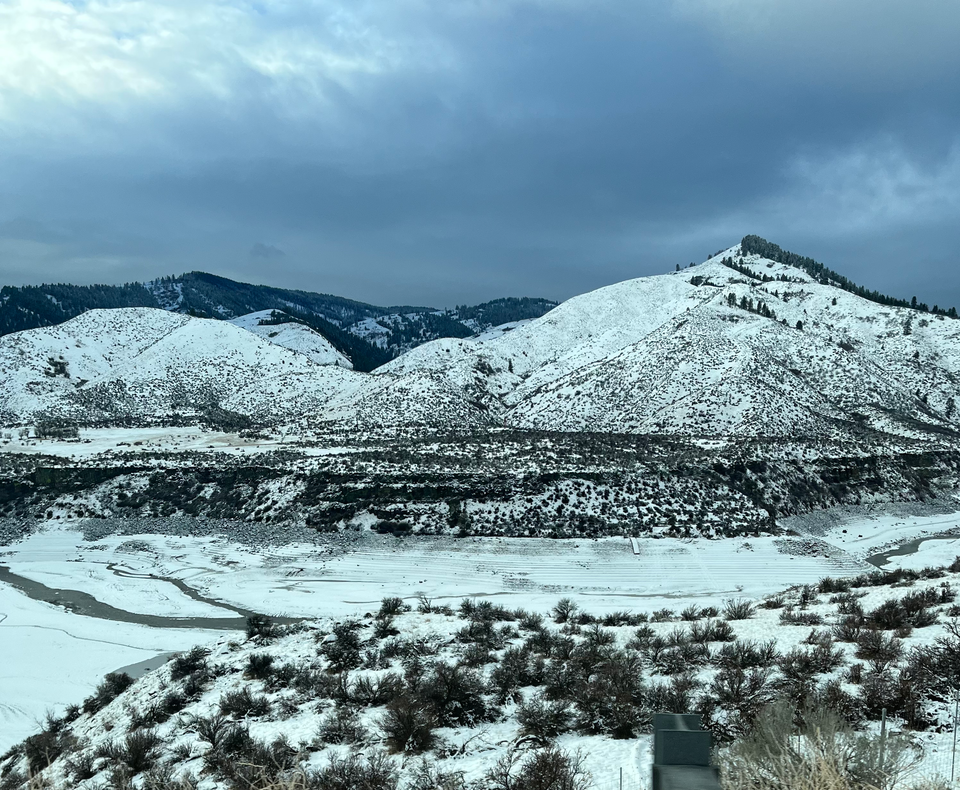 Snowy mountains dotted by tufts of sagebrush. A view from our car window while driving on Highway 55