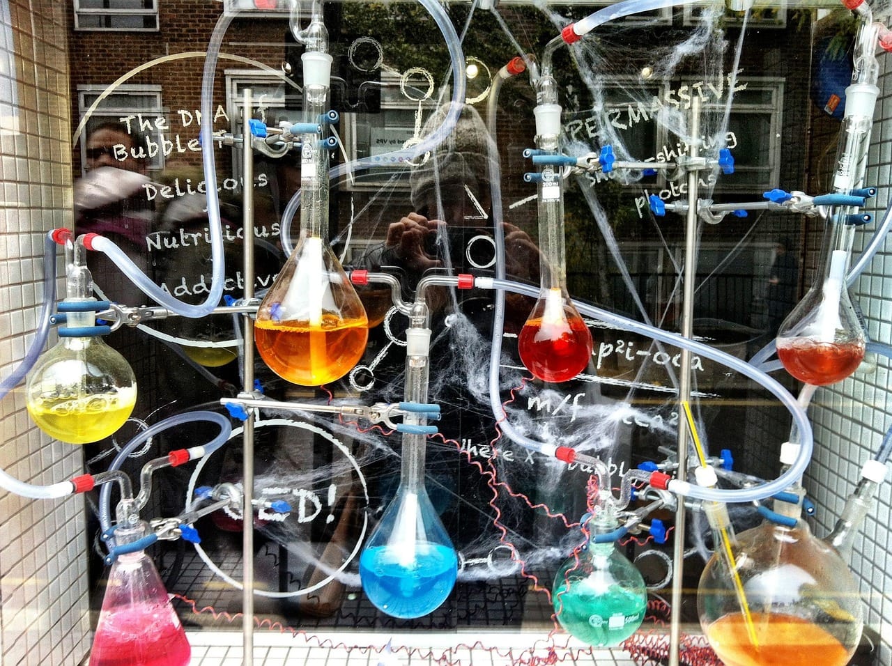 A collectin of round-bottomed, and Erlenmeyer flaskes, all connected with glass and rubber tubing. Each flask contains a colored solution.
