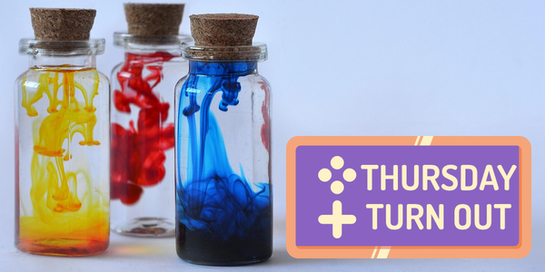A stock photograph showing three glass bottles with cork stoppers. Each bottle has a dye (from left to right: yellow, red, blue) dissolving into water.
